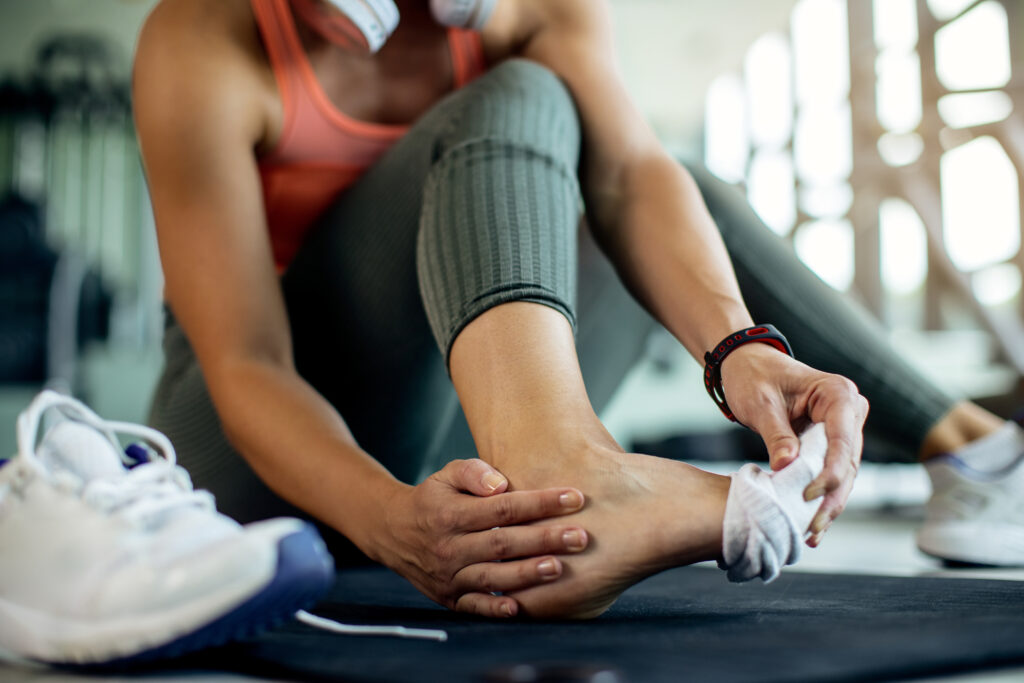 Close-up of athletic woman injured her foot during workout at th